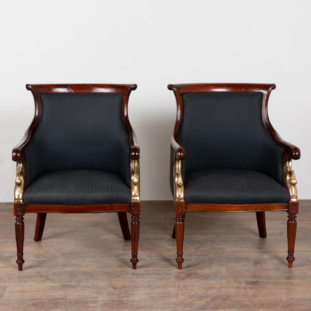 Pair of 19th-century Danish mahogany Biedermeier armchairs featuring elegant curved arms that terminate in scrolls and a...