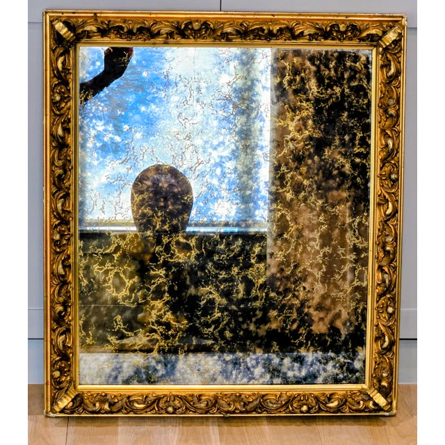 Evocative 28.75 by 32.5 inch antique mirror featuring dramatic, all‑over mercury foxing in a richly carved Rococo Revival...