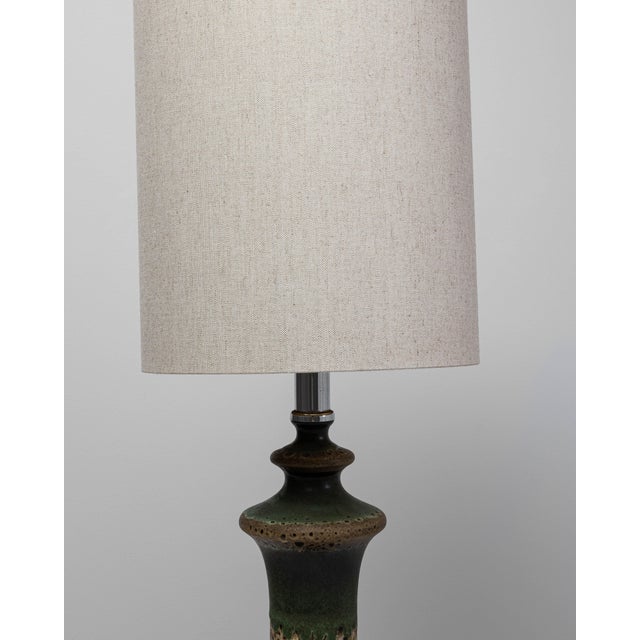 This 1960s German green ceramic table lamp features a sculptural silhouette paired with a richly textured glaze typical of...