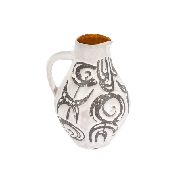 A West German ceramic pitcher produced by Jasba Keramik. This mid-century vase has a white glaze with black biomorphic...