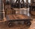 A heavy industrial cart featuring a robust iron and steel framework with large spoked wheels and a wooden slat tambour...