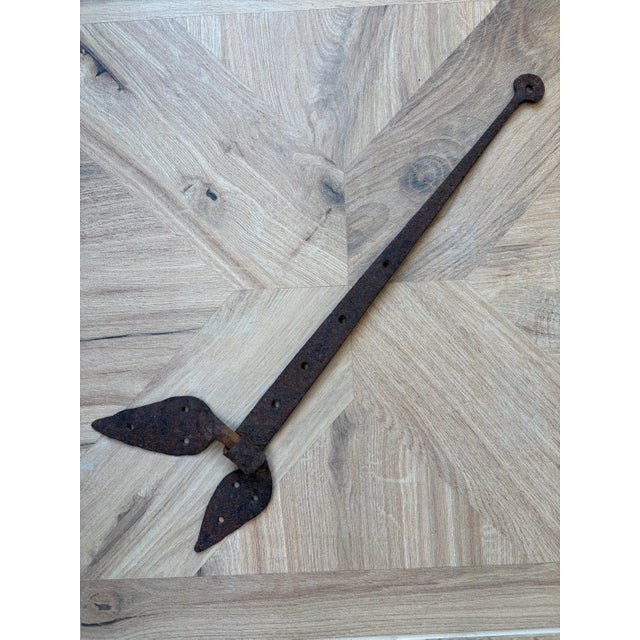 Authentic early 19th-century blacksmith-forged wrought iron strap hinge with decorative hand-shaped leaf terminals....
