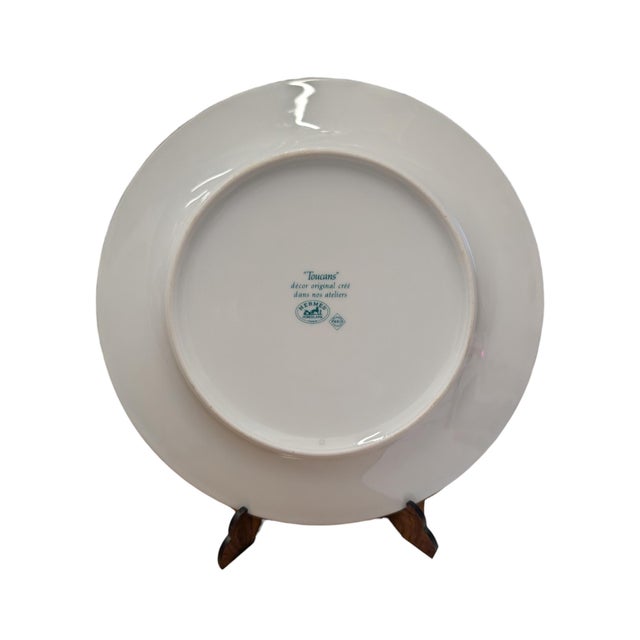 The item shown in the images is a finely decorated porcelain plate from the prestigious 'Toucans' collection by Hermès...