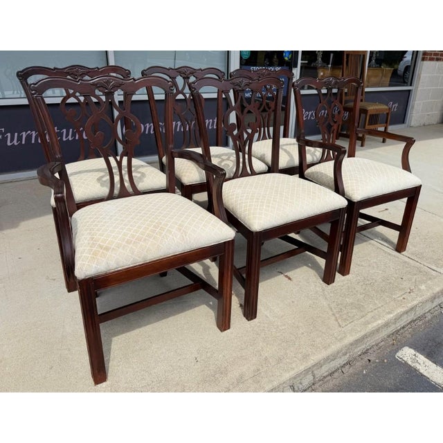 This set of six mahogany Chippendale-style dining chairs features graceful pierced splat backs, carved crest rails, and a...