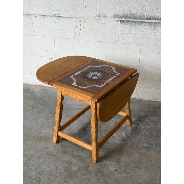 This versatile end table features two folding drop-leaf extensions and an inset ceramic tile top. Turn legs and sturdy...