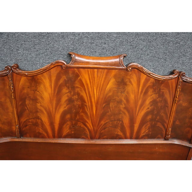Flame mahogany double headboard with shaped crest rail and carved detailing at the top and sides. Features bookmatched...