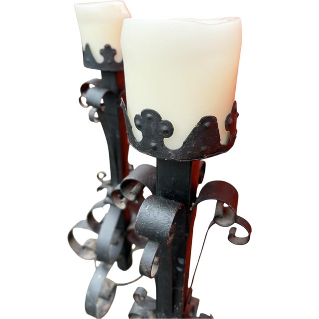 Striking pair of antique hand-forged iron candlesticks featuring elegant scrollwork and classic old-world craftsmanship....