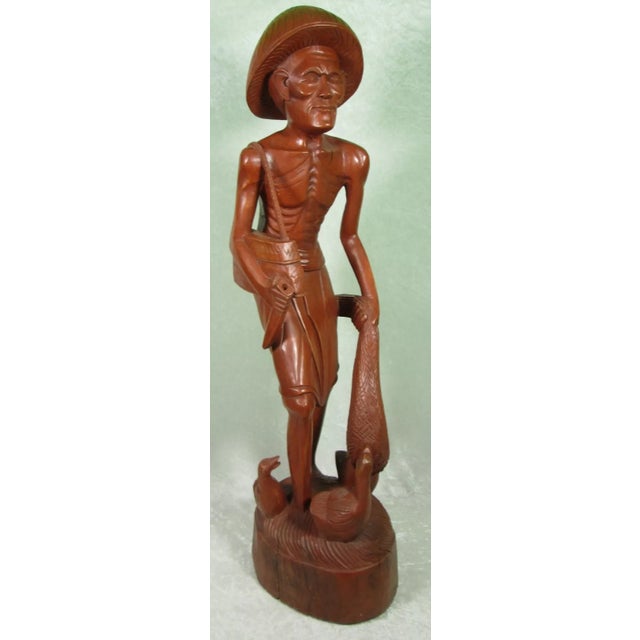 Hand Carved Wood Asian Fisherman Figurine. The Japanese fisherman is holding a bag over his right shoulder and holding a...