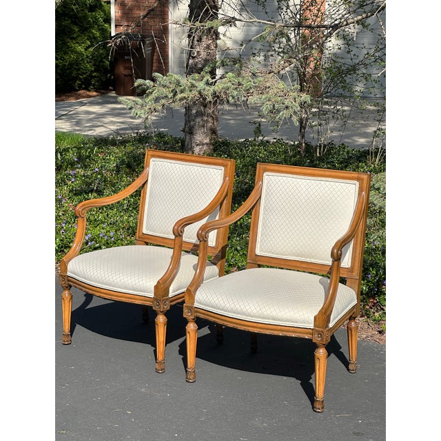 Pair of neoclassical style armchairs believe to be by Hickory chair. Medium-tone wood frame with subtly carved details...