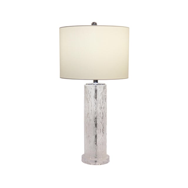 This elegant table lamp features a clear, vertically textured glass base that creates a striking visual effect,...