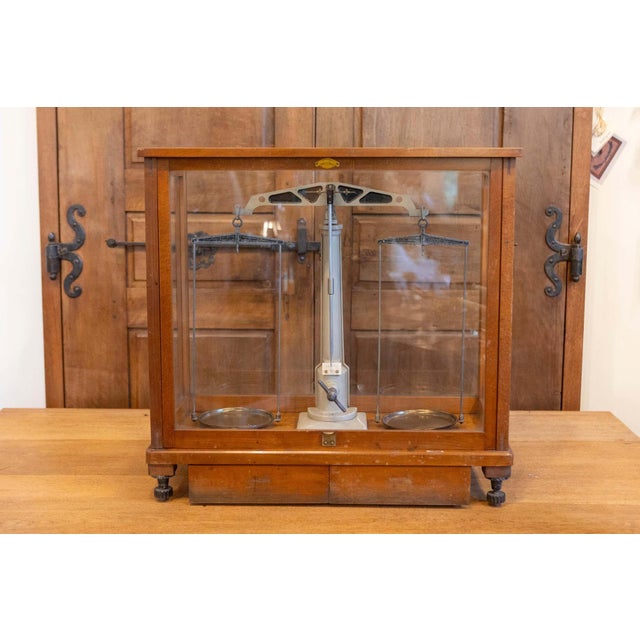 This 20th-century German scale encased in a glass and wood frame is a fine example of precision engineering and functional...