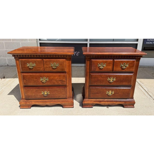 This pair of Chippendale-style nightstands features warm wood tones, traditional brass bail hardware, and handsome molded...