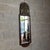 A majestic and imposing vertical wooden wall mirror with a sumptuous heraldic frieze in embossed brass and beveled glass,...