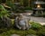 A hand-carved, solid agate Buddha. He is depicted sitting with his robe open, cinched with a bow under his belly, an...