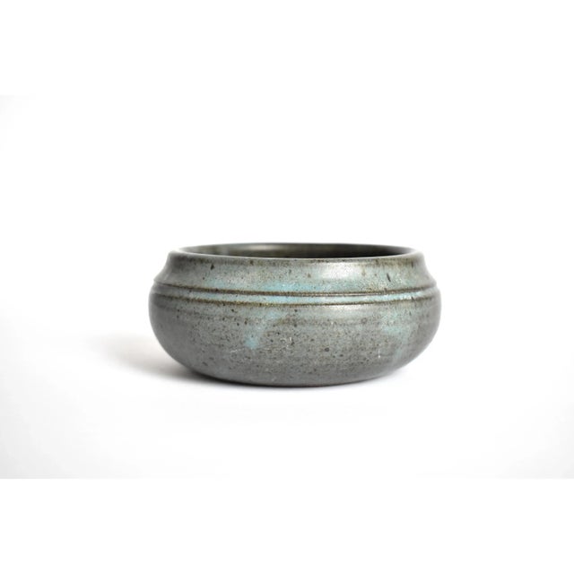 A vintage studio or art pottery small round earthenware bowl, with a ridged top border and a green-grey glaze. Stamped on...