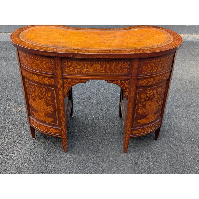 This exceptional Continental kidney-form desk exhibits master craftmanship, featuring exquisite satinwood marquetry inlay...