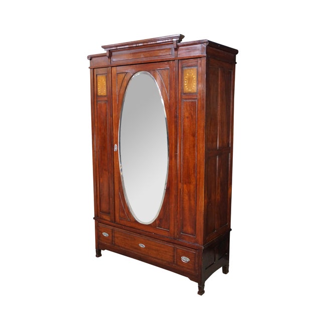 This elegant Edwardian Neoclassical knockdown armoire is masterfully crafted from rich mahogany wood and adorned with...