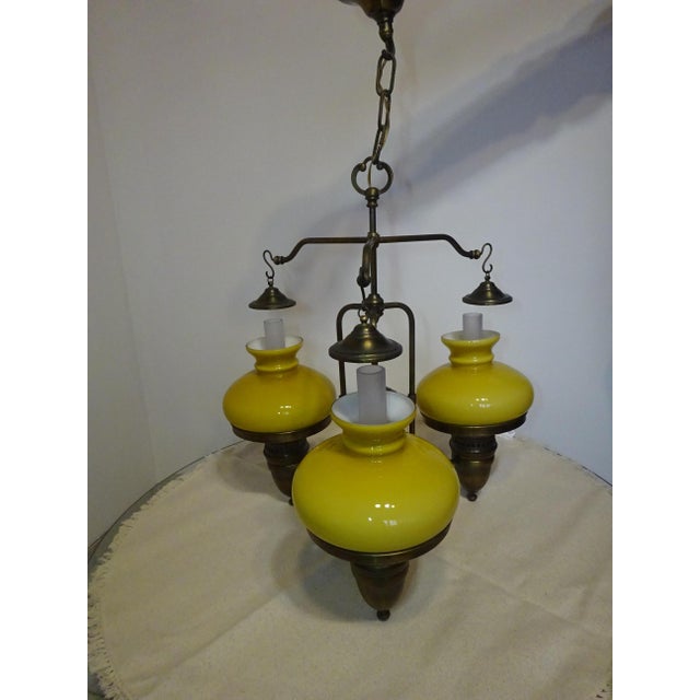 Complete chandelier from the 1970s, with an imposing brass frame, three frosted white glass shades shaped like oil lamps,...