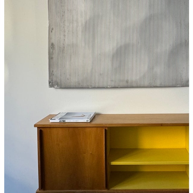 Very good condition for this ‘Antony’ wall-mounted bookcase in maple wood and yellow lacquer, sliding door. This piece has...