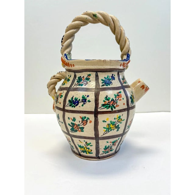 Old Italian clay work basket jug. Coiled handles with hand painted floral around the body. This beautiful vintage piece...