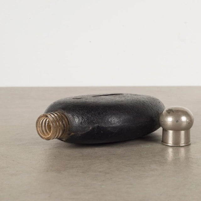 ABOUT An original leather covered flask with screw top lid, thick glass interior and window on both sides. CREATOR...