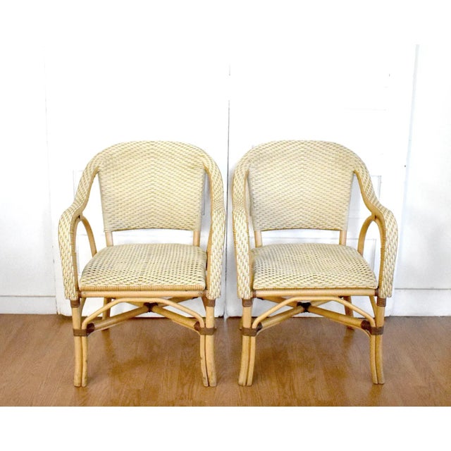 A set of 4 outdoor dining chairs in the style of French wicker bistro chairs or Serena and Lily rattan "Riviera"...