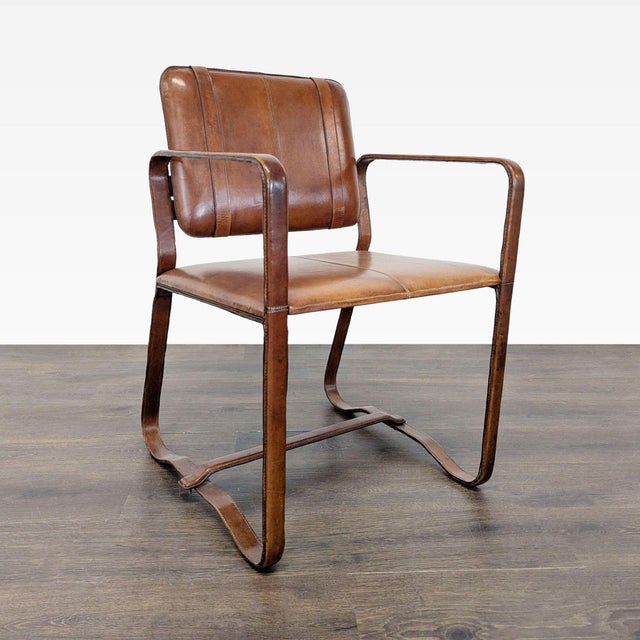 This lounge chair features a sturdy curved wooden frame and a rich brown leather seat and backrest. The armrests and...