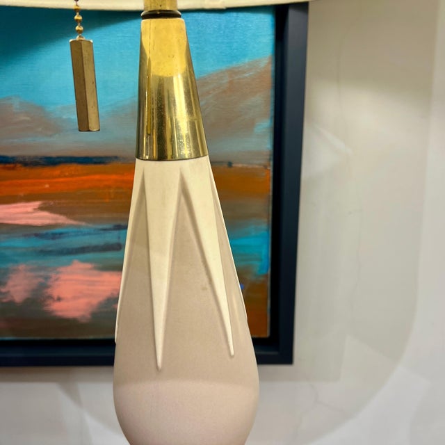 A modernist ceramic table lamp designed by Gerald Thurston. Cream and brown ceramic form with patinated brass base and...