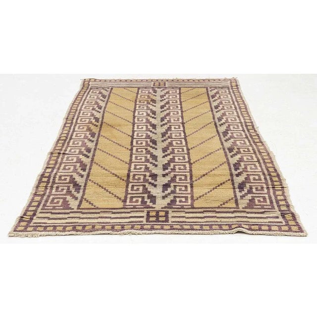 Stricking 1930s Swedish rug. The background of the pile is a pale mustard colour with a decorative block border with a...
