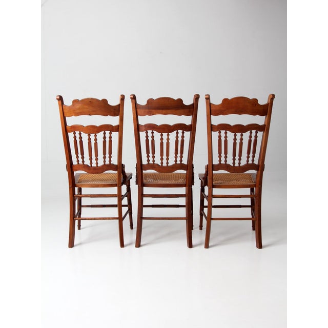 A set of three early 20th-century Eastlake Revival dining chairs blending American Country Victorian styling with carved...