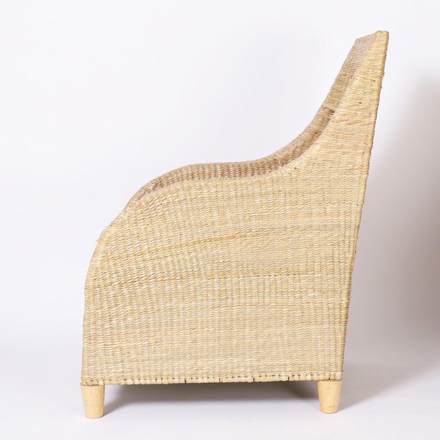Chic pair of mid century inspired armchair crafted in wicker or reed ambitiously woven over a sturdy metal frame.