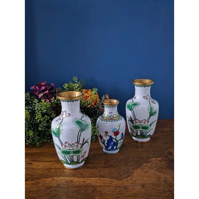 Exquisite set of three vintage Chinese cloisonné vases, hand-enameled with intricate floral and bird motifs over a classic...
