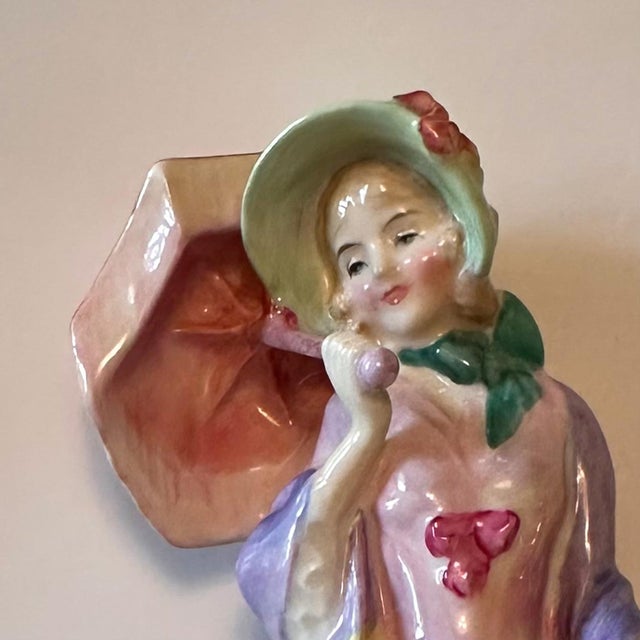 A vintage Royal Doulton “Miss Demure” figurine in finely glazed English bone china, featuring soft pastel coloration and...