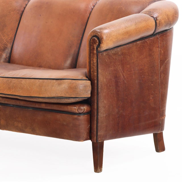 A handsome Dutch leather sofa in the Art Deco style, circa 1960. The three-seat form features gracefully curved back and...