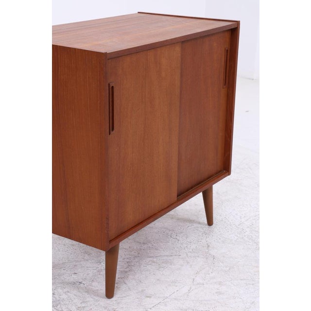 Vintage teak chest of drawers with clean lines and practical sliding doors. The slender, tapered legs and beautiful grain...