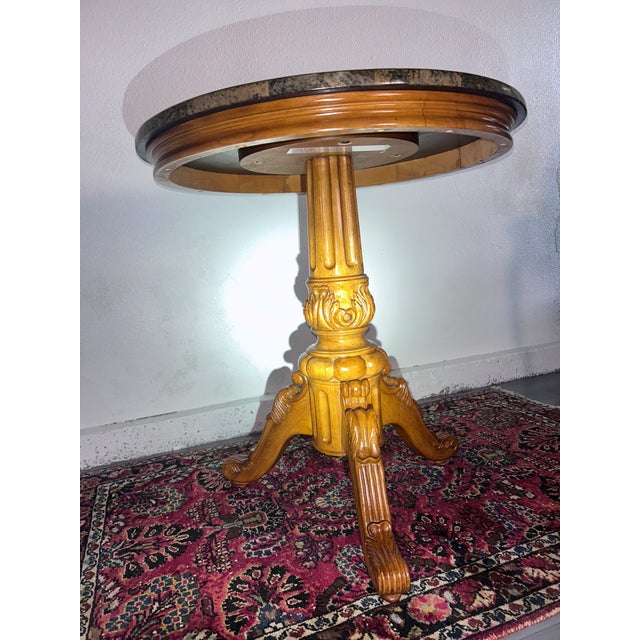 Elegant traditional pedestal accent table featuring a round black marble-look top with decorative stone border and a...
