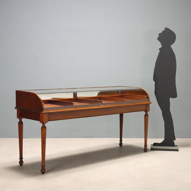 Walnut display cabinet. Curved glass top, pair of drawers with a drop-front door and internal mirror. Four carved...