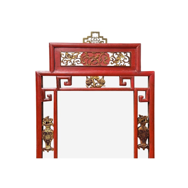 This striking Chinese-style wall mirror features a rectangular frame crafted from wood with a vibrant, aged cinnabar-red...
