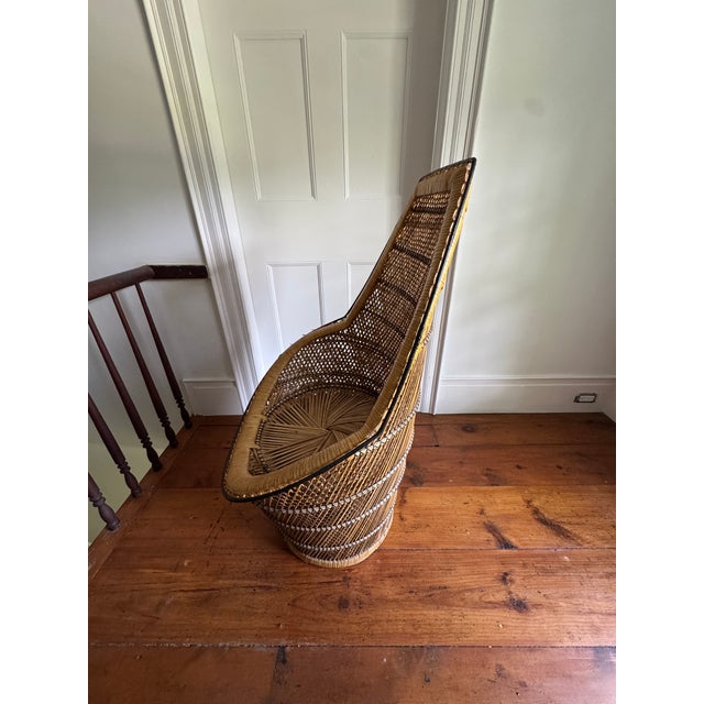A striking vintage Emmanuelle chair — the iconic hooded, cone-back peacock chair popularized in the 1970s boho revival....