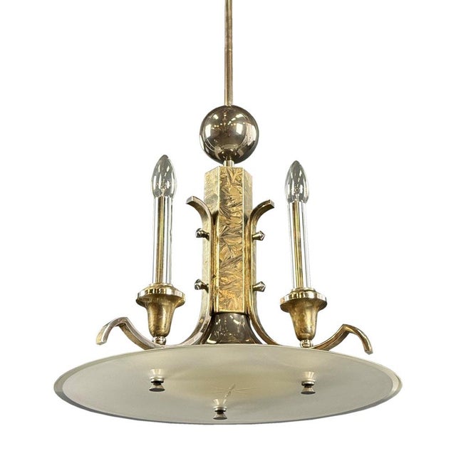 A refined Art Deco chandelier featuring a striking central element with intricate metalwork. The centerpiece is decorated...