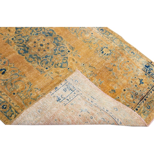 Beautiful vintage Persian distressed hand-knotted wool rug with a tan color field. This piece has a navy blue frame and...