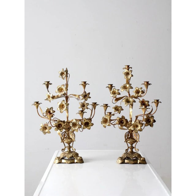 A pair of late 19th-century antique brass candelabras, each featuring seven candleholders arranged among an elaborate...