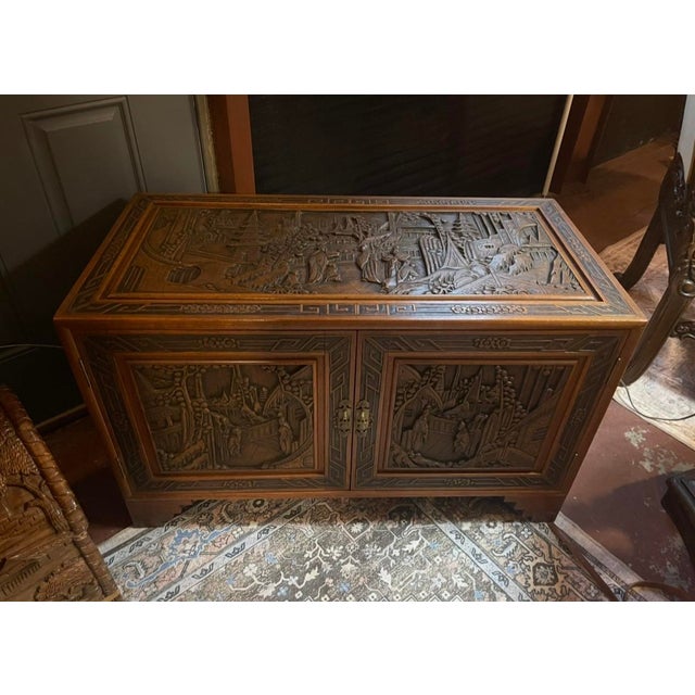 An extraordinary Asian-inspired carved wood cabinet showcasing intricate craftsmanship, rich wood tones, and beautifully...