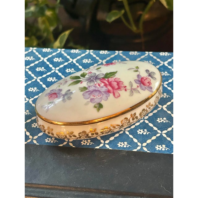 A charming vintage Limoges porcelain trinket box handcrafted in France. This petite oval box features delicate hand-...