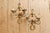 Pair of two-arm brass wall sconces, featuring an elegant design of scrolls and curves inspired by classical style, with a...