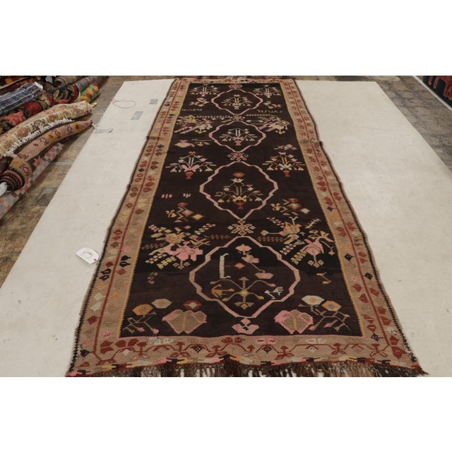 Handwoven in a wool flat weave originating from Turkey circa 1950-1960, this vintage Kilim rug enjoys a mid-century...