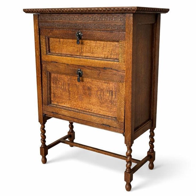 A beautifully proportioned antique oak cabinet featuring a compact two-tier design, raised on elegant turned legs with...