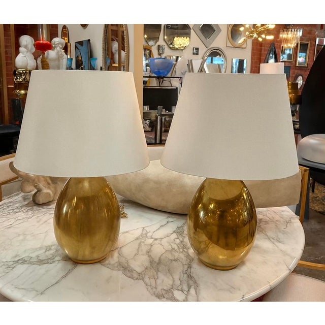 Elevate your space with this elegant pair of table lamps featuring a warm, reflective brass base and classic tapered cream...