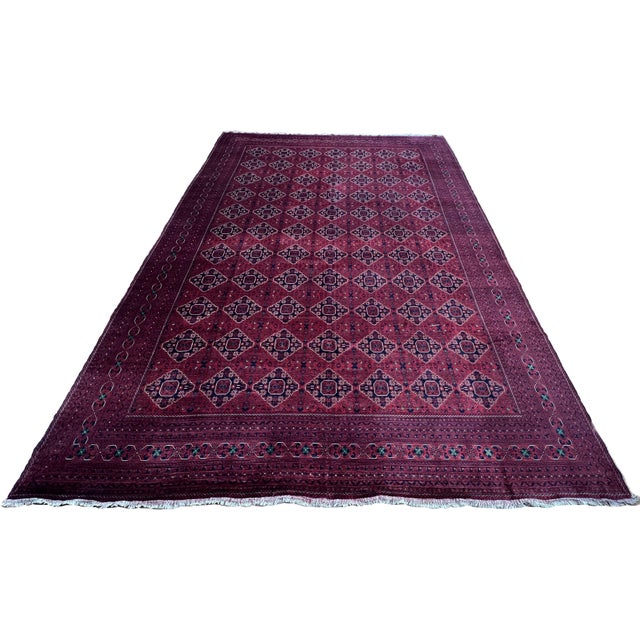 Afghan Turkmen rug, hand knotted in Afghanistan from 100% wool. Measuring 13’1” x 19’2”, the rug features a rich burgundy...