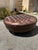 Traditional Chesterfield-style round deep-buttoned tufted leather ottoman, featuring a rich brown distressed leather...
